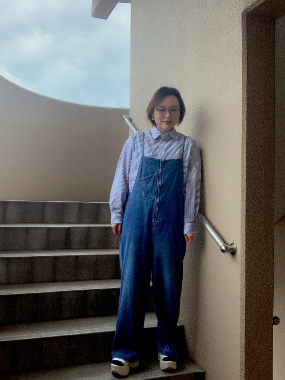 ブルー系のシャツ/ブラウス、ブルー系のサロペット/オーバーオール、ホワイト系のサンダルを着用したレディースの春コーディネートの2枚目の写真