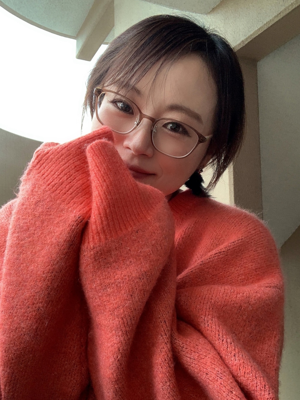 オレンジ系のニット/セーター、ブラック系のチノパンツ、ブラック系のブーツを着用したレディースの冬コーディネートの3枚目の写真