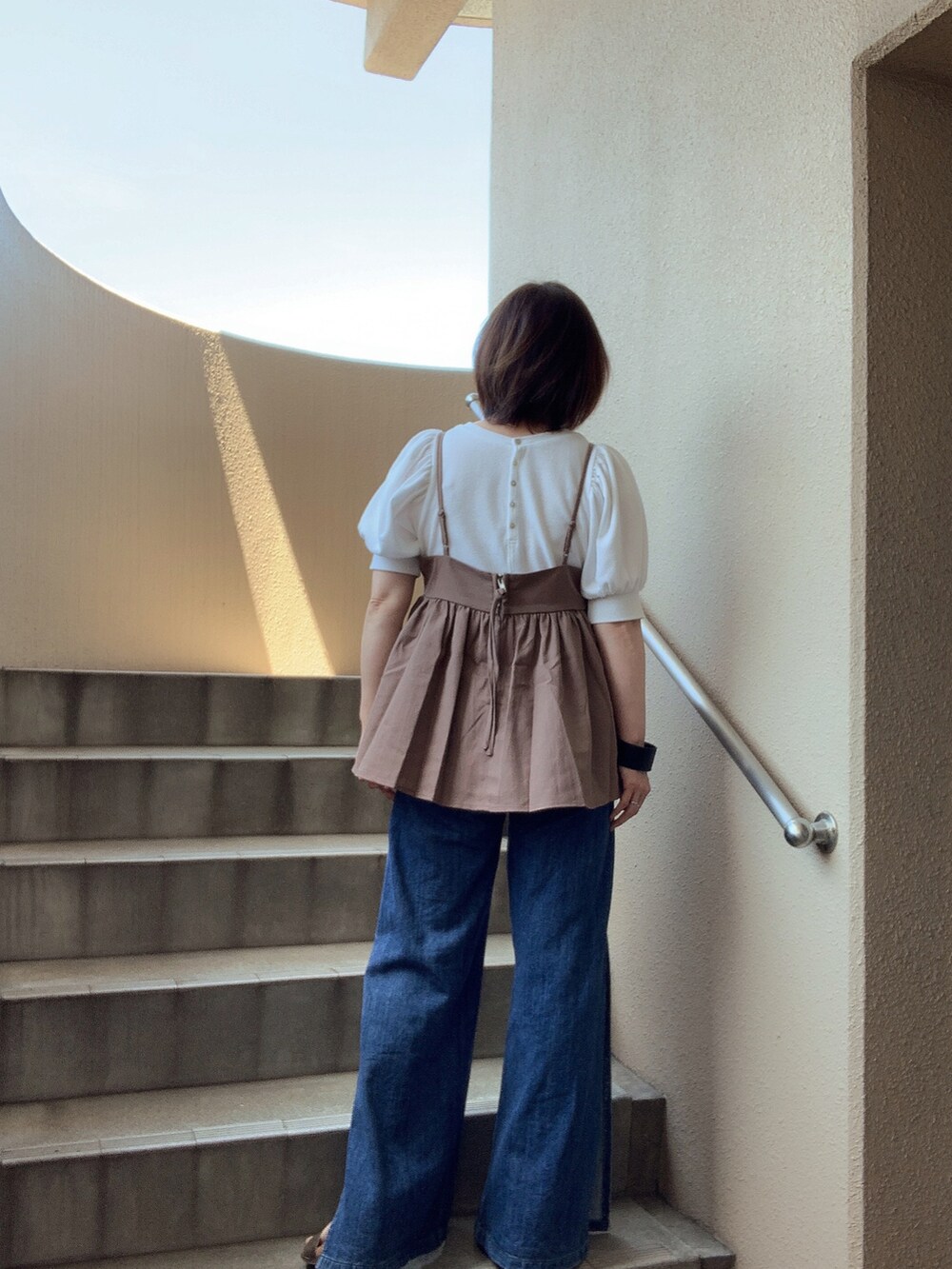 ブルー系のデニムパンツ、ホワイト系のTシャツ/カットソー、ブラウン系のキャミソールを着用したレディースの夏コーディネートの4枚目の写真