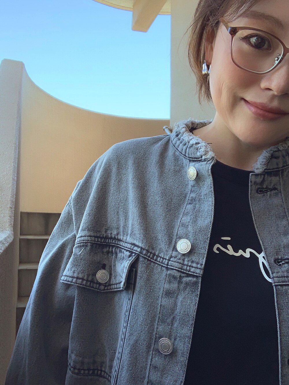 ブラック系のデニムジャケット、ブラック系のTシャツ/カットソー、ホワイト系のスカートを着用したレディースの春コーディネートの3枚目の写真
