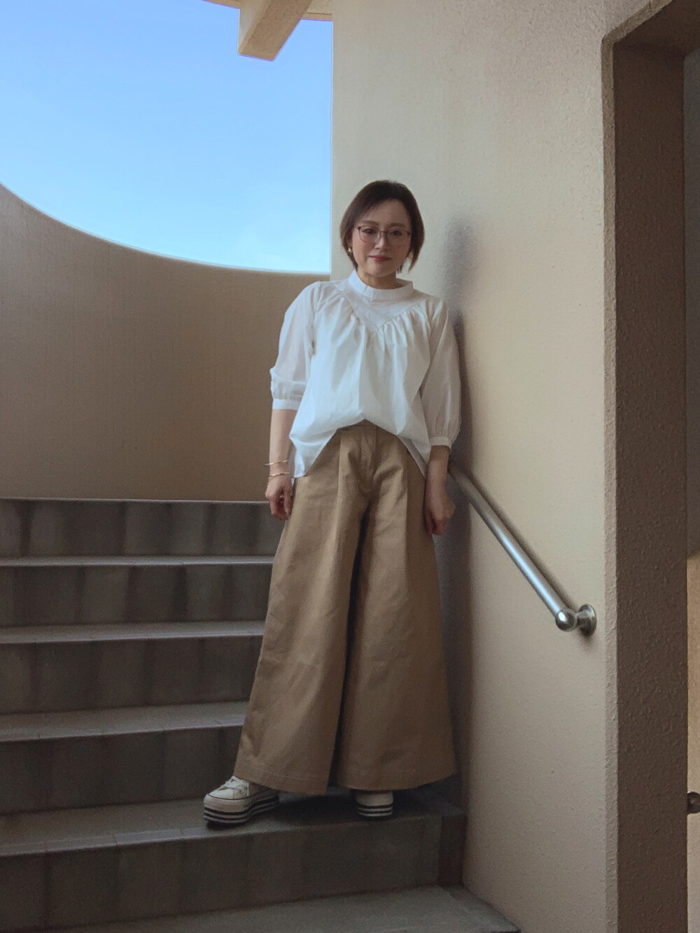 ホワイト系のシャツ/ブラウス、ベージュ系のチノパンツ、ホワイト系のスニーカーを着用したレディースの春コーディネートの2枚目の写真