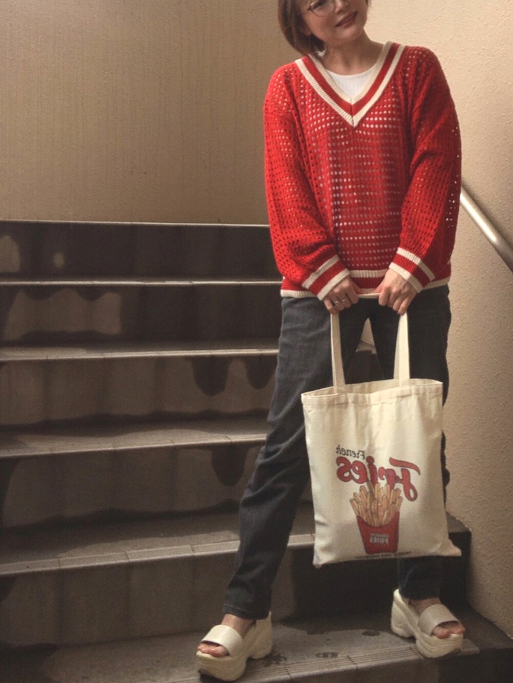 レッド系のニット/セーター、ホワイト系のタンクトップ、ブラック系のデニムパンツを着用したレディースの春コーディネートの2枚目の写真