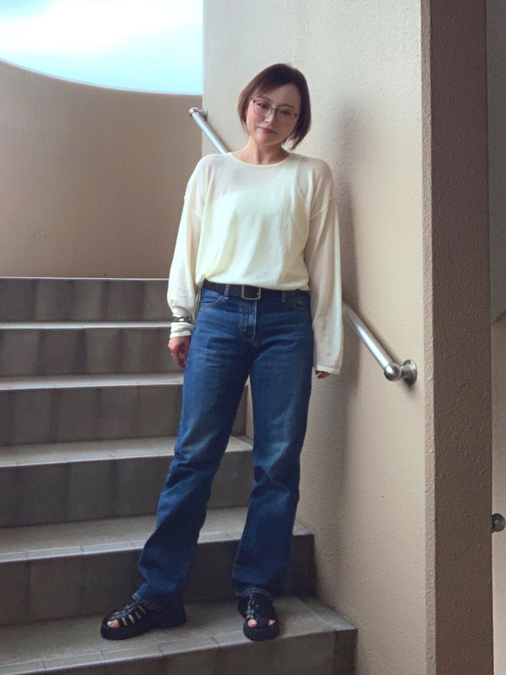 イエロー系のニット/セーター、ホワイト系のタンクトップ、ブルー系のデニムパンツを着用したレディースの春コーディネートの2枚目の写真