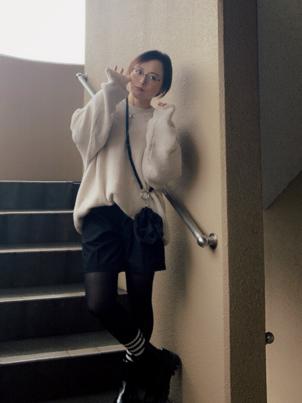 ブラック系のベスト、ホワイト系のニット/セーター、ブラック系のチノパンツを着用したレディースの冬コーディネートの4枚目の写真