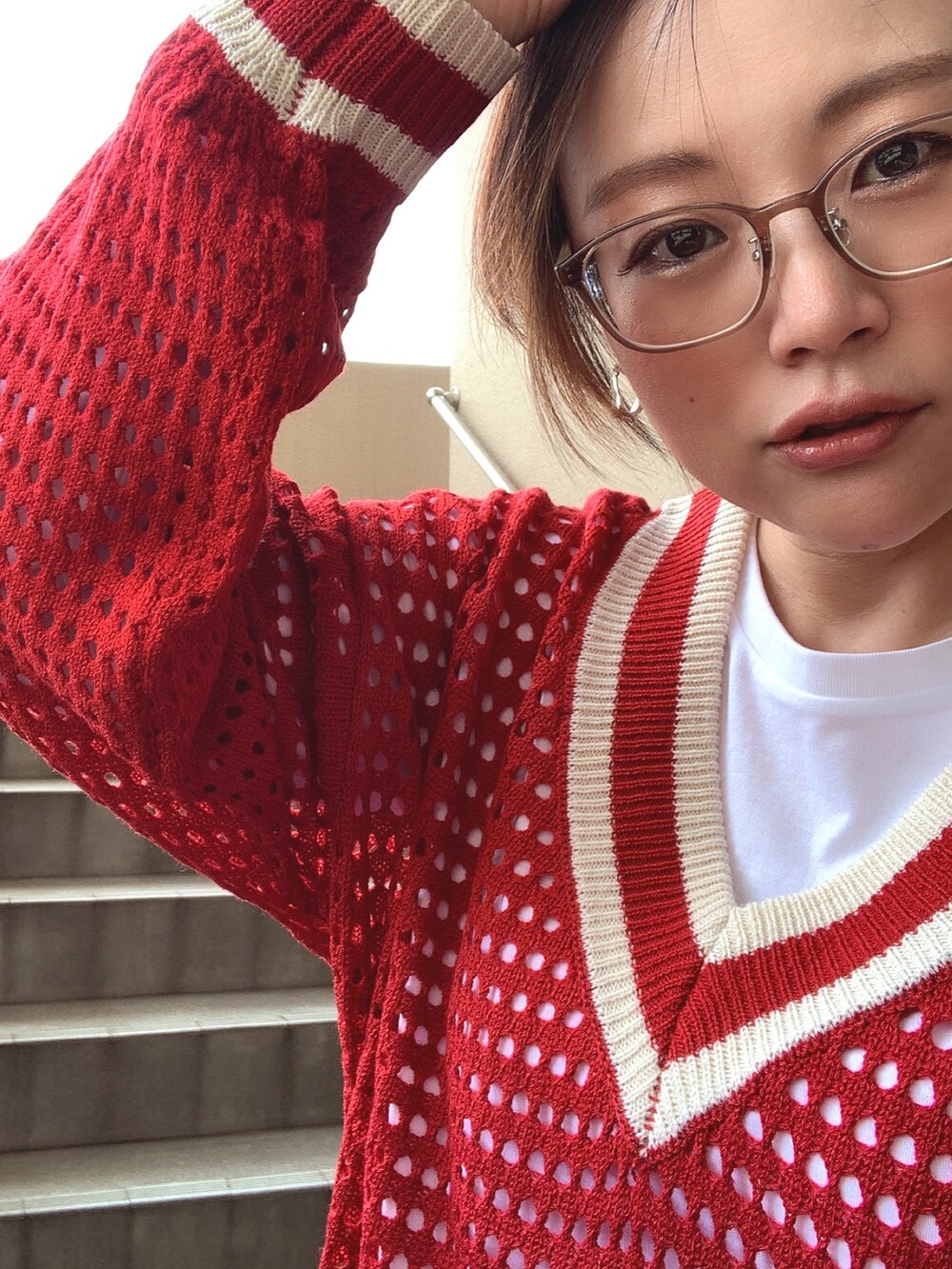 レッド系のニット/セーター、ホワイト系のTシャツ/カットソー、ブルー系のデニムパンツを着用したレディースの春コーディネートの4枚目の写真