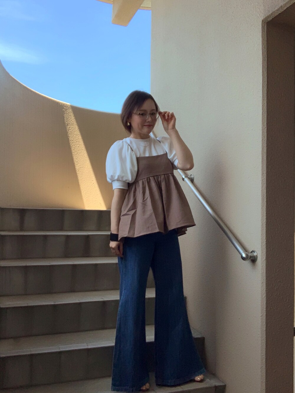 ブルー系のデニムパンツ、ホワイト系のTシャツ/カットソー、ブラウン系のキャミソールを着用したレディースの夏コーディネートの3枚目の写真