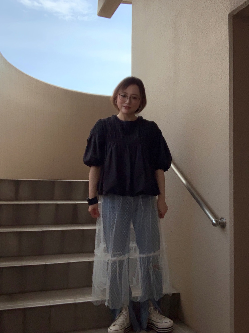 ホワイト系のスカート、ブルー系のデニムパンツ、ホワイト系のスニーカーを着用したレディースの夏コーディネートの3枚目の写真