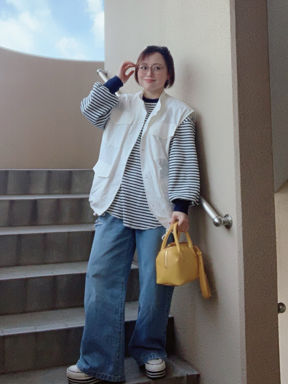 ホワイト系のベスト、ブルー系のTシャツ/カットソー、ブルー系のデニムパンツを着用したレディースの春コーディネートの3枚目の写真