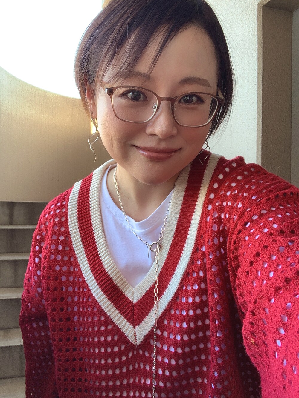 レッド系のニット/セーター、ホワイト系のTシャツ/カットソー、ブルー系のデニムパンツを着用したレディースの秋コーディネートの2枚目の写真