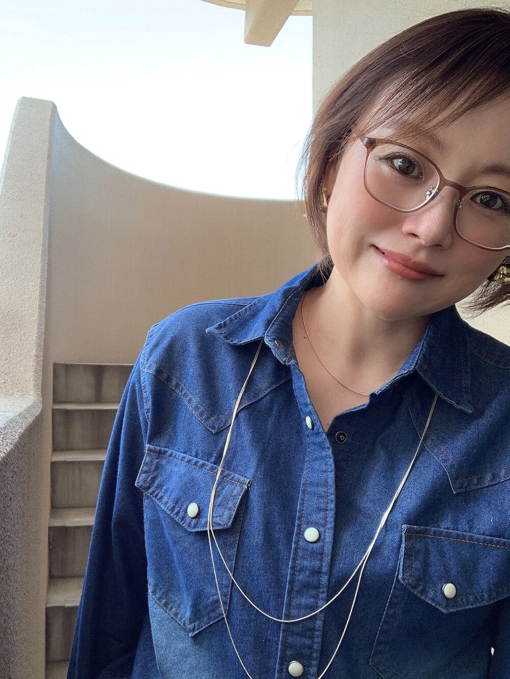 ブルー系のシャツ/ブラウス、ブルー系のデニムパンツ、ホワイト系のスニーカーを着用したレディースの春コーディネートの2枚目の写真