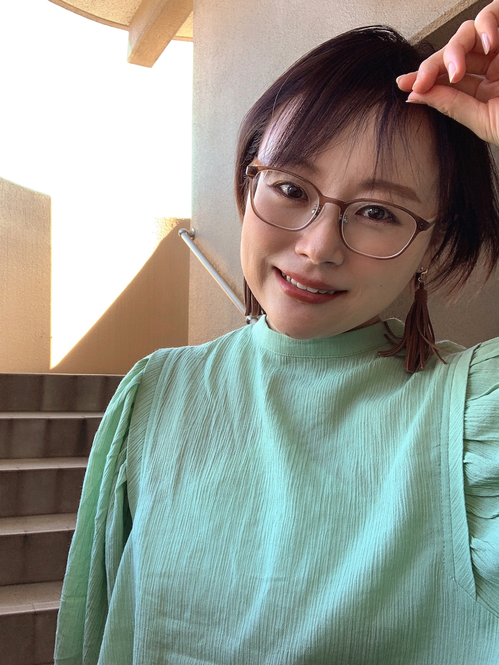 グリーン系のシャツ/ブラウス、ホワイト系のキャミソール、ブルー系のデニムパンツを着用したレディースの秋コーディネートの2枚目の写真