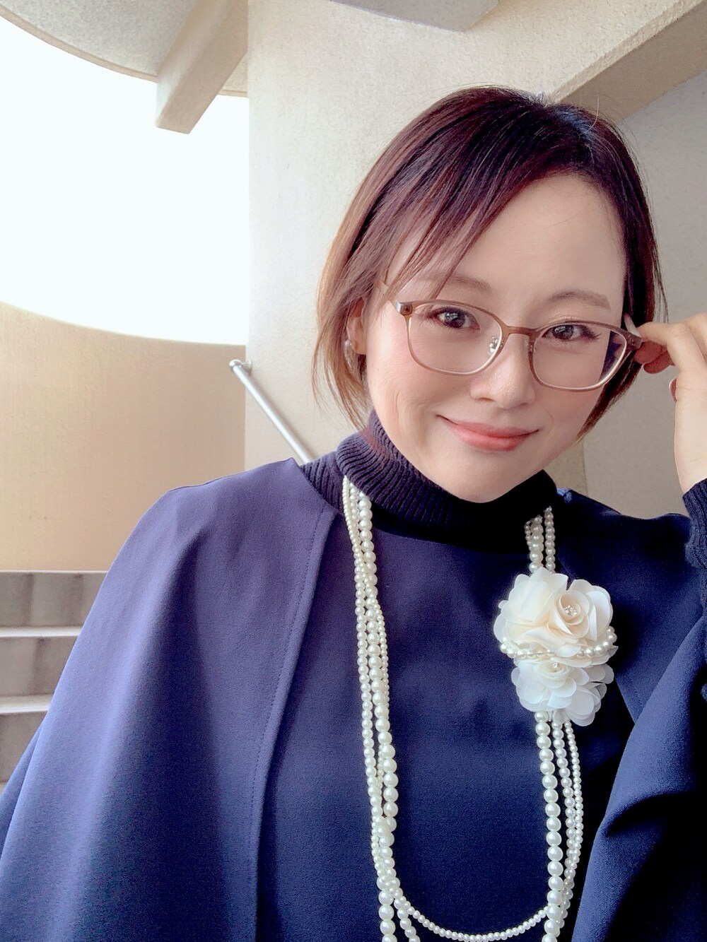 ブルー系のフォーマルスーツ/小物、ブラック系のブーツ、ホワイト系のブローチ/コサージュを着用したレディースの春コーディネートの2枚目の写真