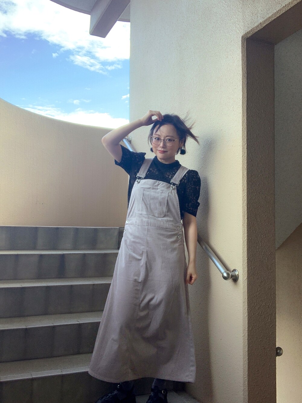 グレー系のジャンパースカート、ブラック系のシャツ/ブラウス、ブラック系のサンダルを着用したレディースの秋コーディネートの4枚目の写真