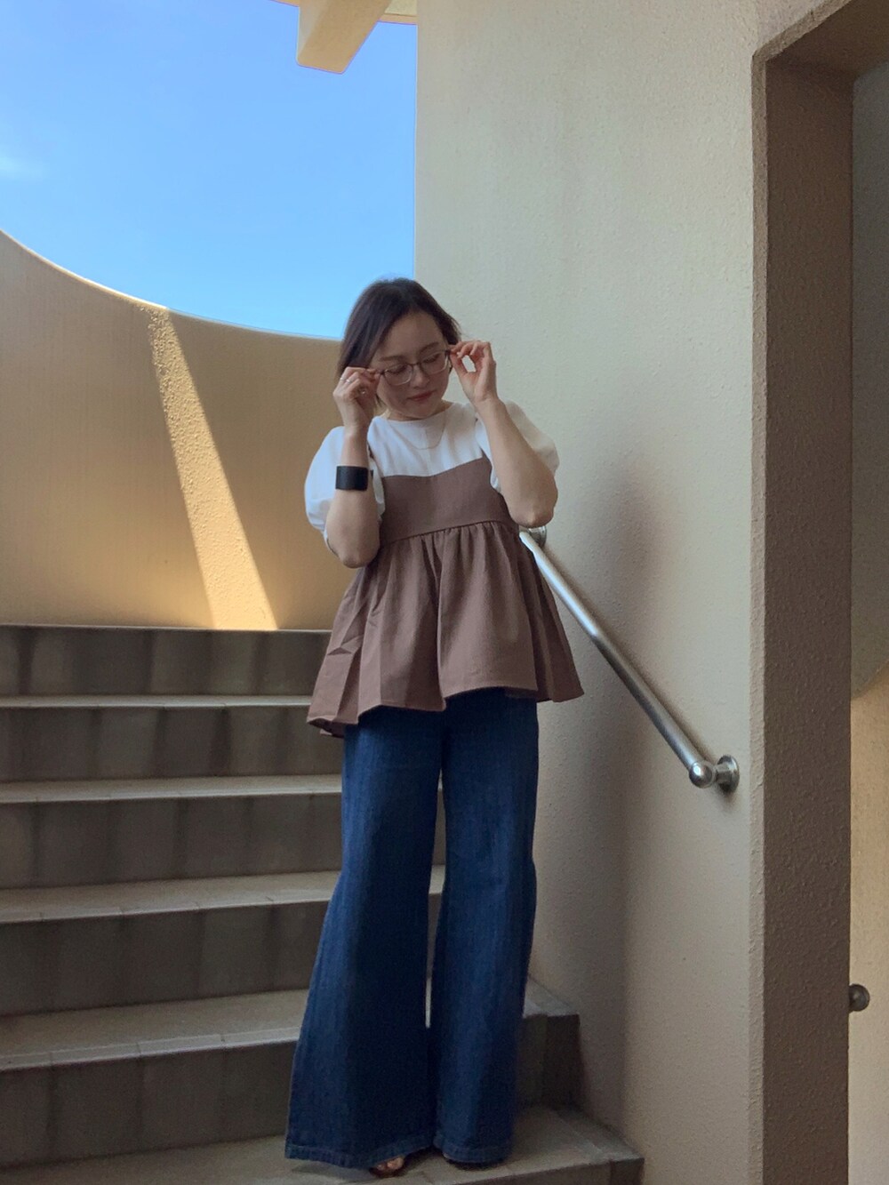 ブルー系のデニムパンツ、ホワイト系のTシャツ/カットソー、ブラウン系のキャミソールを着用したレディースの夏コーディネートの2枚目の写真