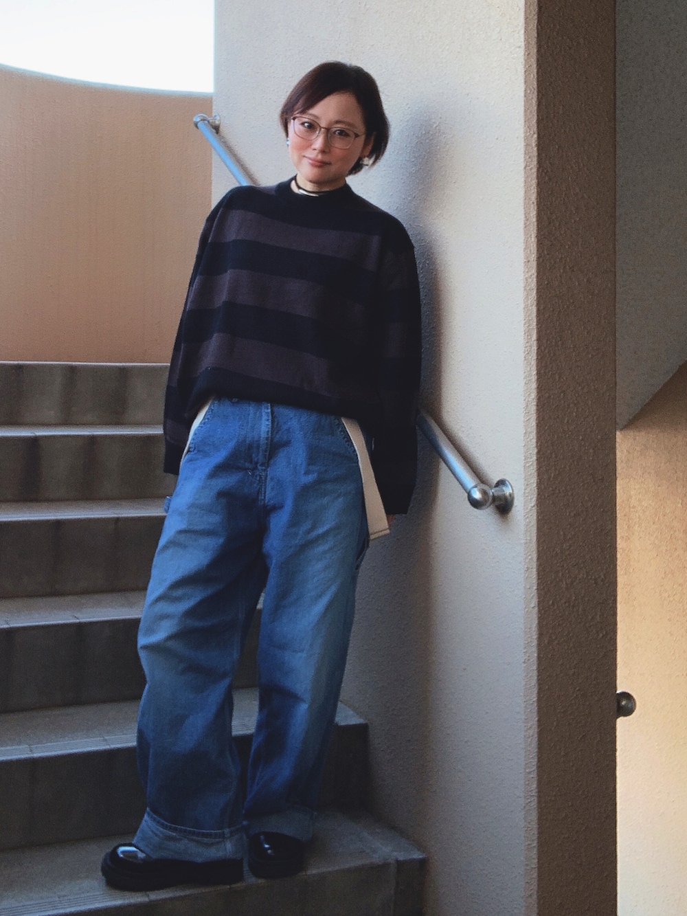 ブラック系のニット/セーター、ブルー系のサロペット/オーバーオール、ブラック系のブーツを着用したレディースの秋コーディネートの3枚目の写真