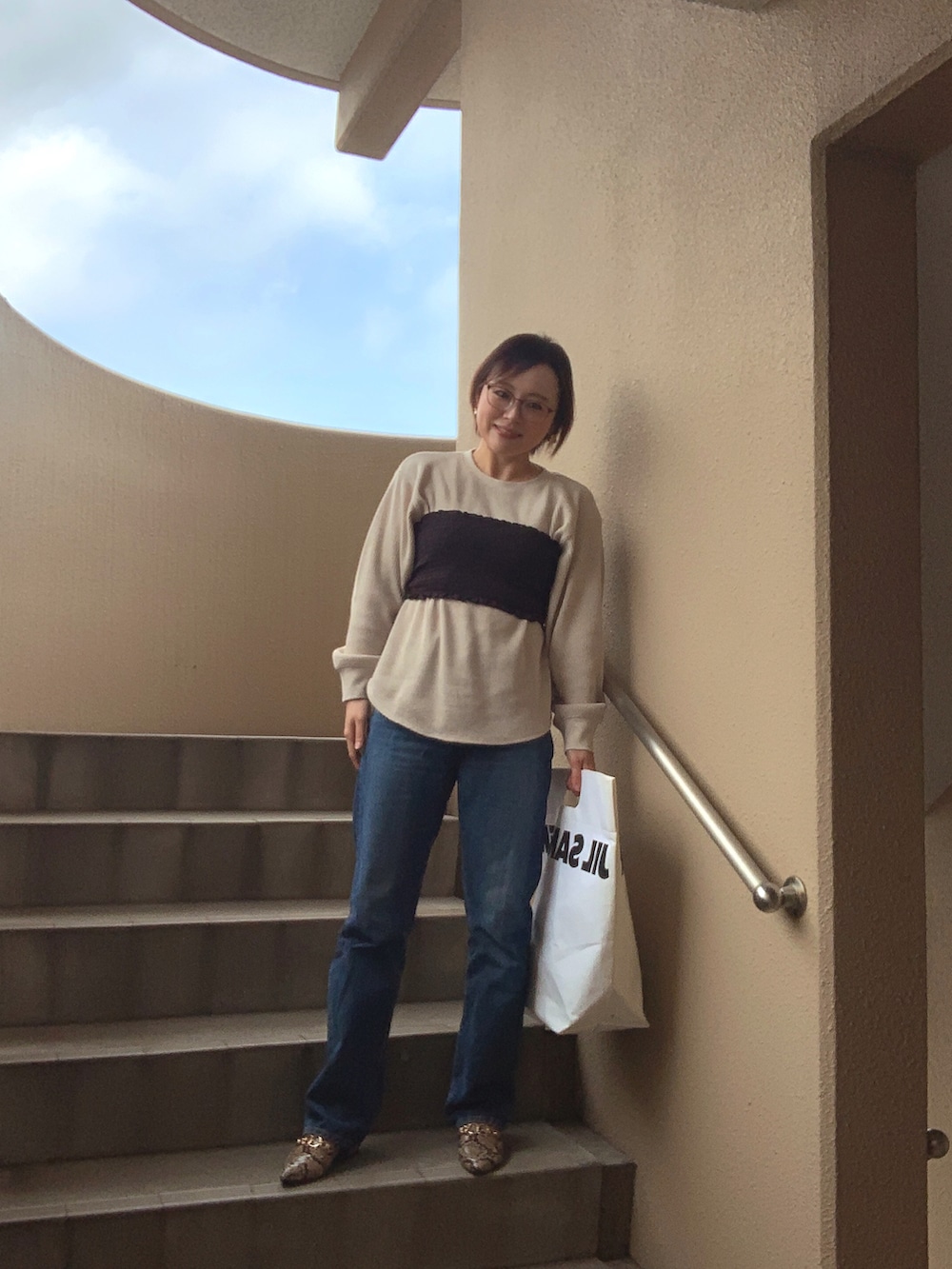 ブラック系のチューブトップ、ベージュ系のTシャツ/カットソー、ブルー系のデニムパンツを着用したレディースの春コーディネートの2枚目の写真