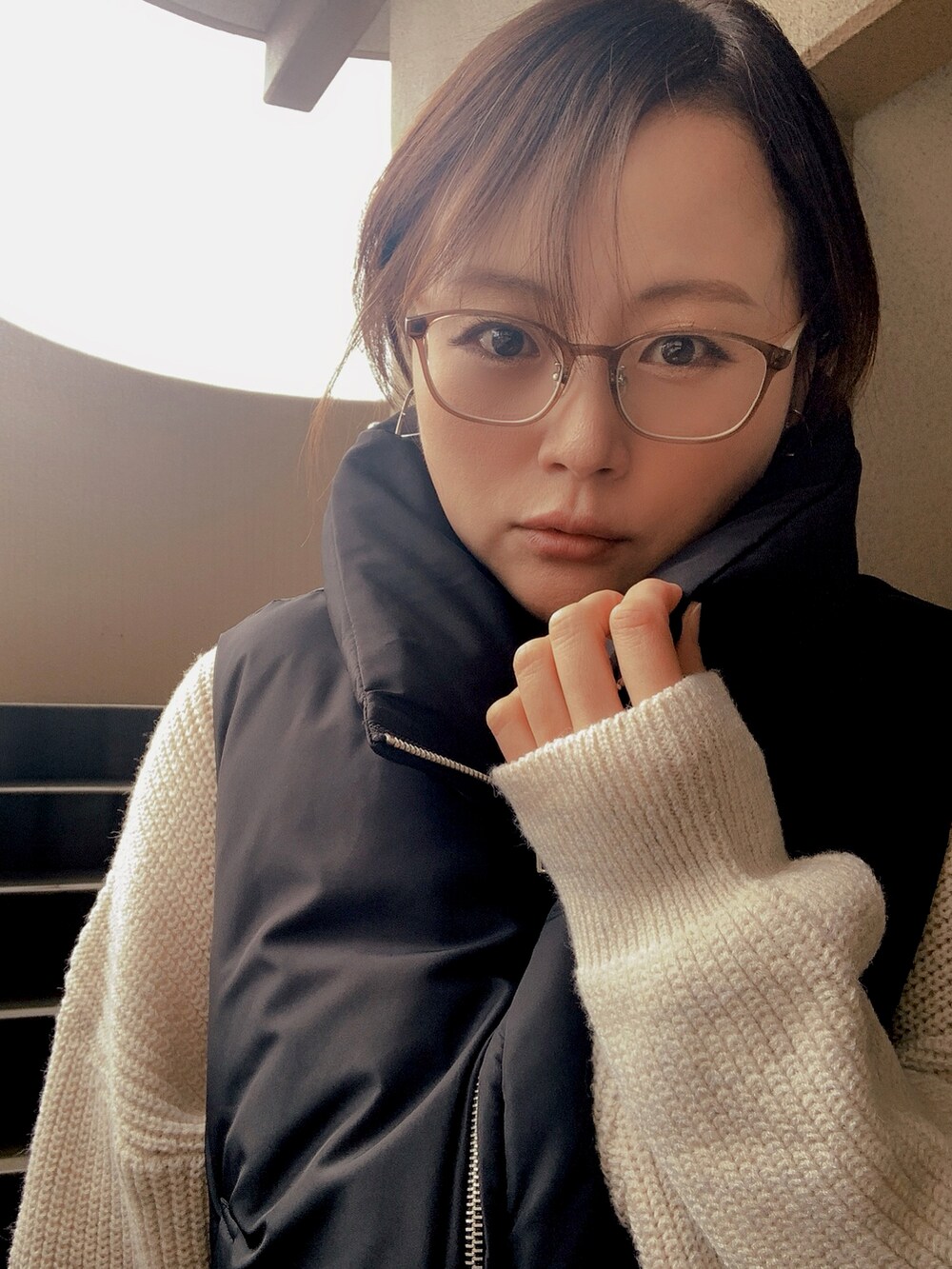 ブラック系のベスト、ホワイト系のニット/セーター、ブラック系のチノパンツを着用したレディースの冬コーディネートの3枚目の写真