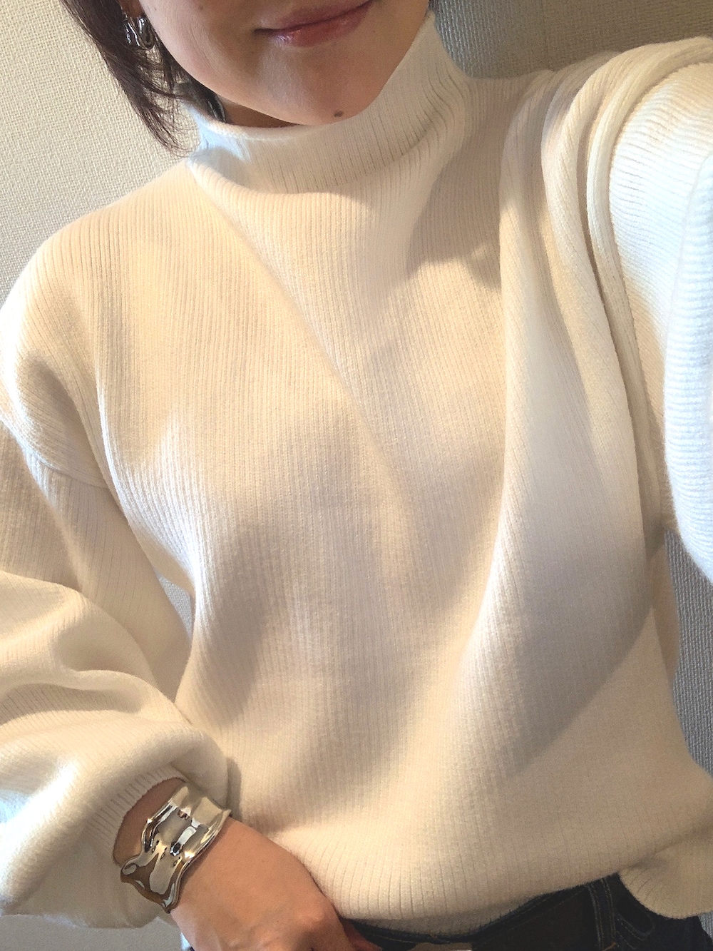 ホワイト系のニット/セーター、ブルー系のスラックス、ブラック系のブーツを着用したレディースの冬コーディネートの3枚目の写真