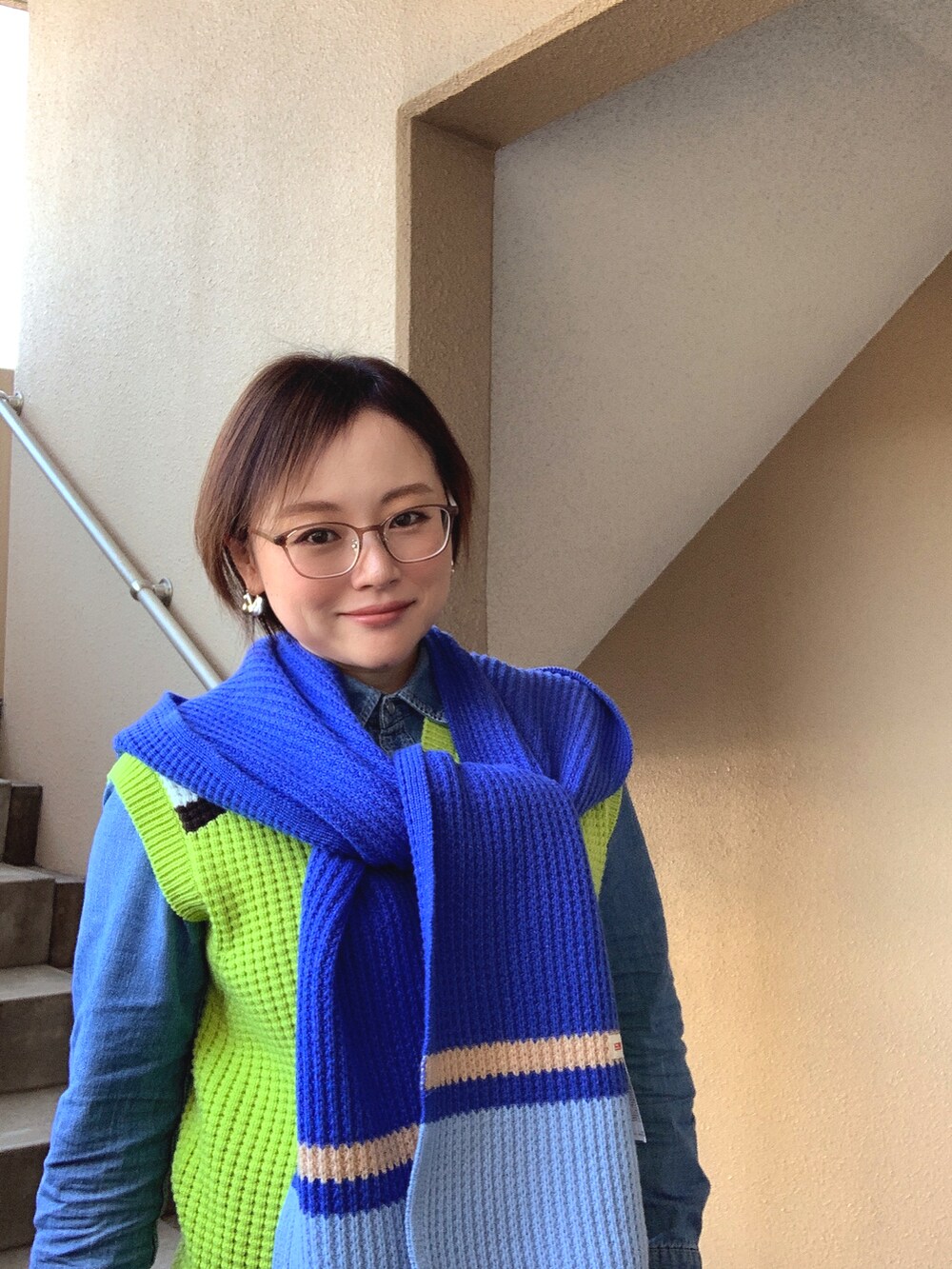 ブルー系のシャツ/ブラウス、グリーン系のベスト、ブルー系のデニムパンツを着用したレディースの春コーディネートの2枚目の写真