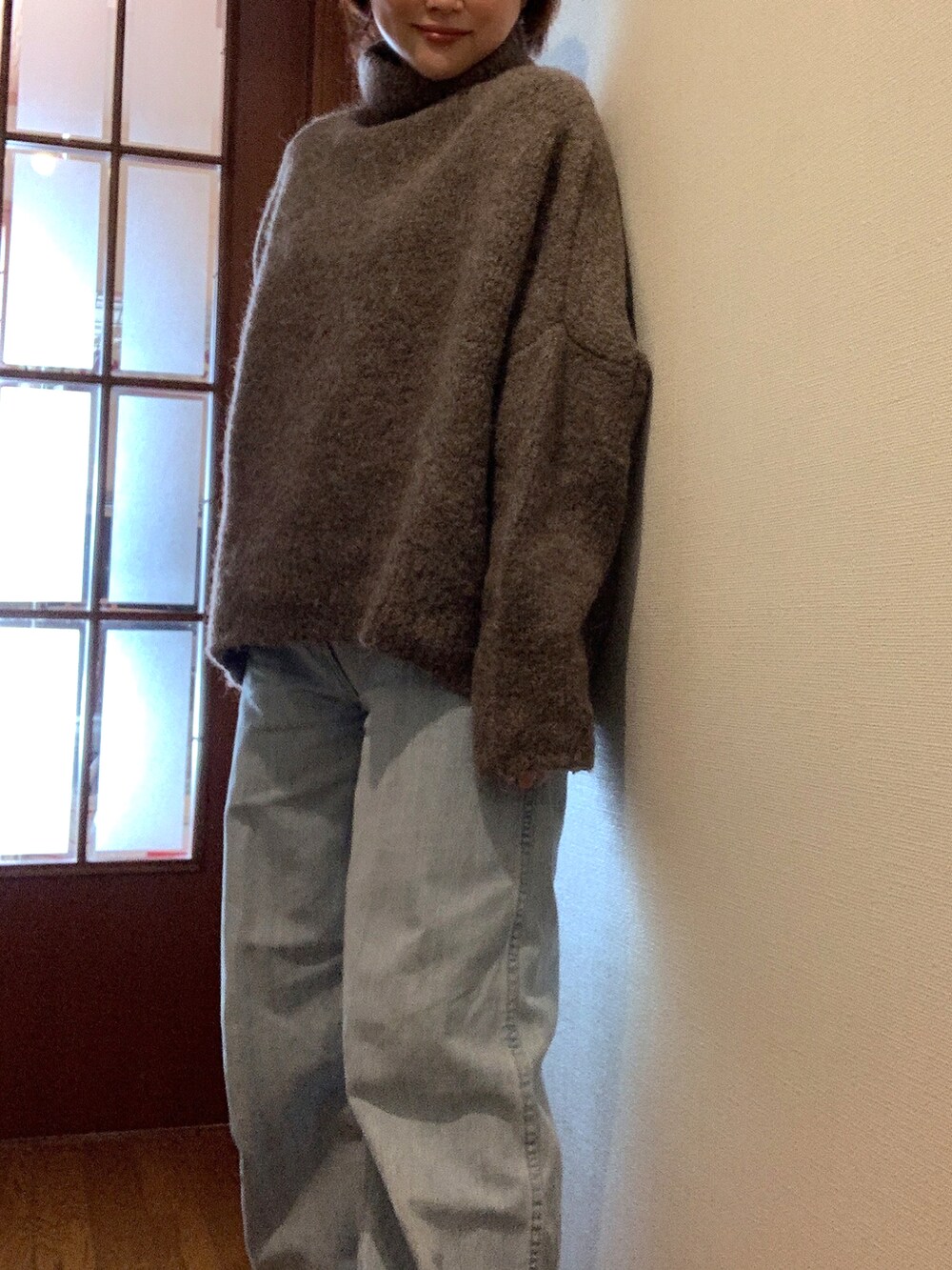 ブラウン系のニット/セーター、ブルー系のデニムパンツ、ブラック系のブーツを着用したレディースの冬コーディネートの2枚目の写真