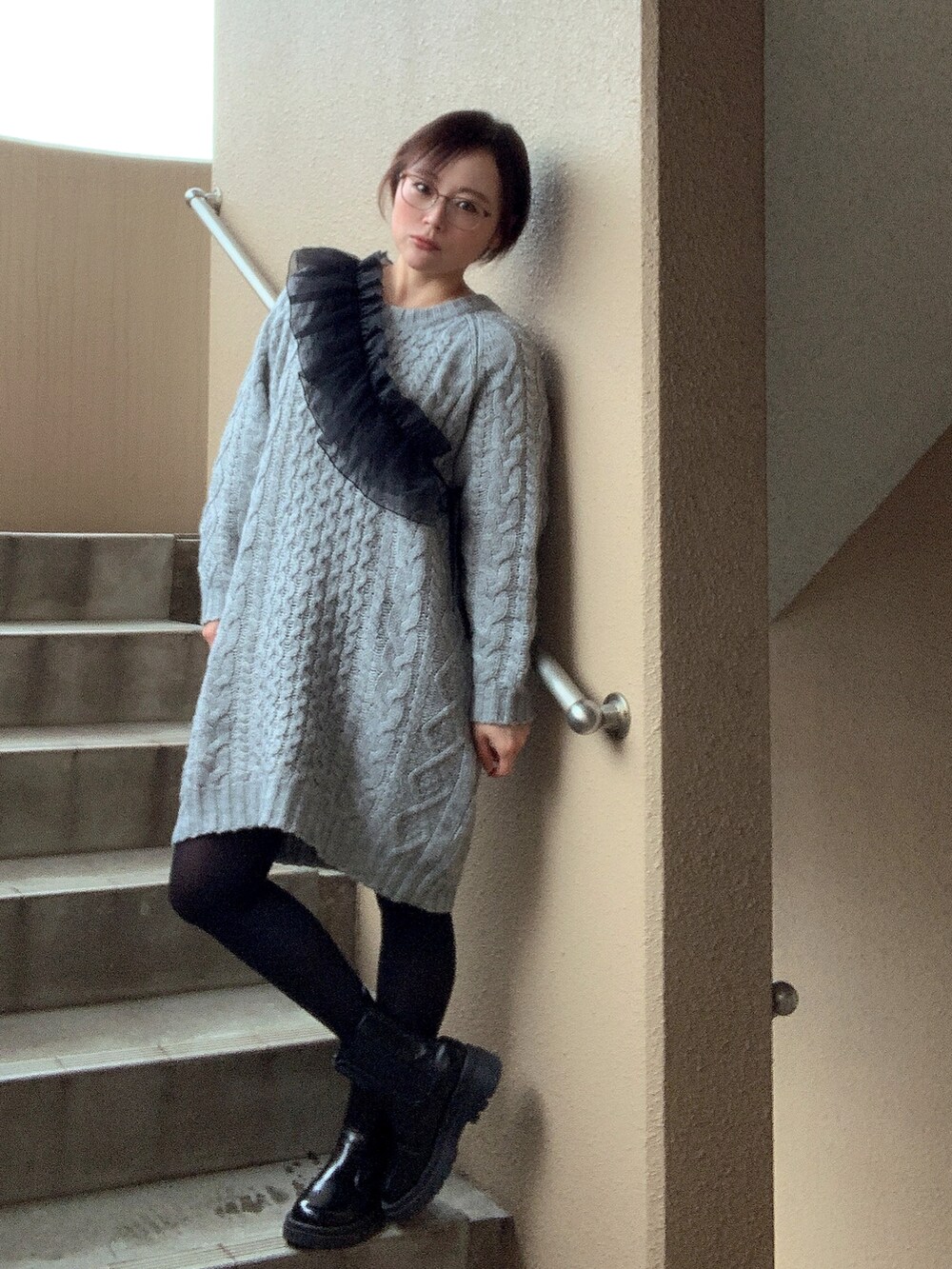 グレー系のワンピース、ブラック系のブーツ、ブラック系の付け襟を着用したレディースの冬コーディネートの2枚目の写真