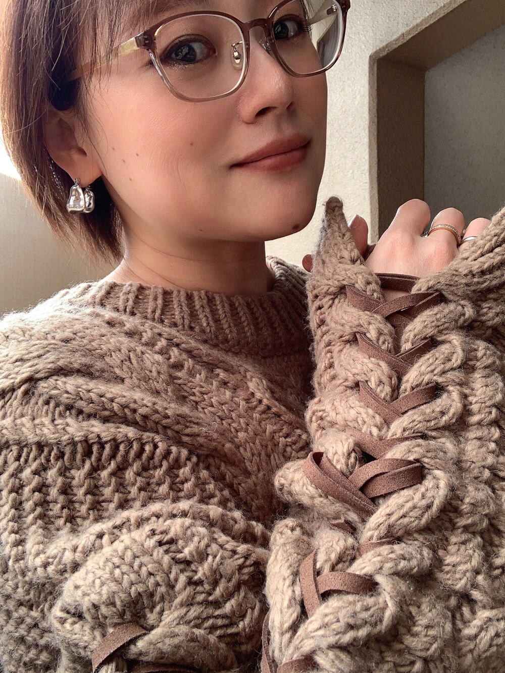 ブルー系のデニムパンツ、ブラウン系のニット/セーター、ブラック系のブーツを着用したレディースの冬コーディネートの2枚目の写真