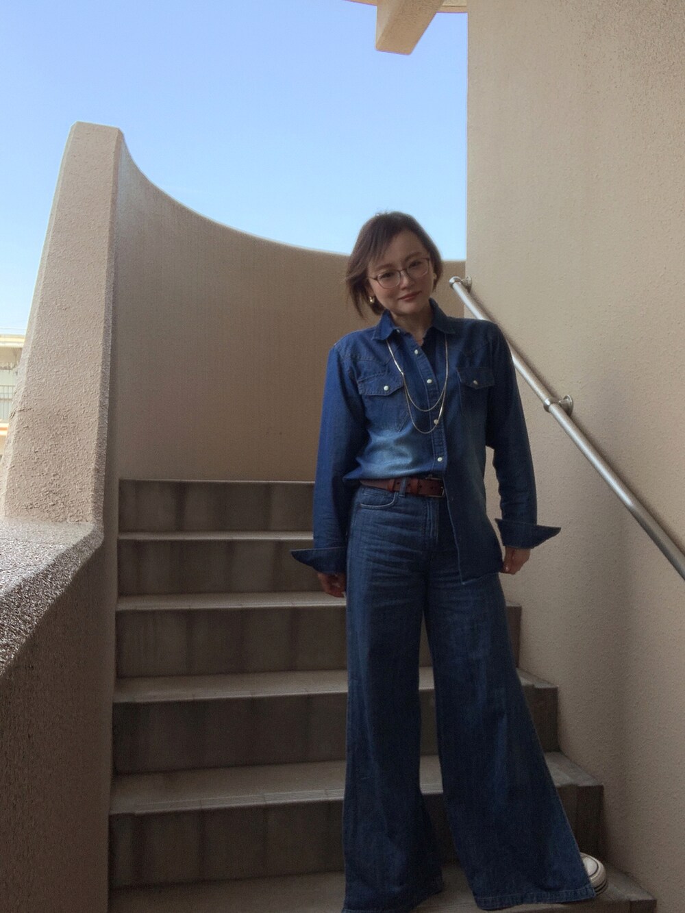 ブルー系のシャツ/ブラウス、ブルー系のデニムパンツ、ホワイト系のスニーカーを着用したレディースの春コーディネートの3枚目の写真