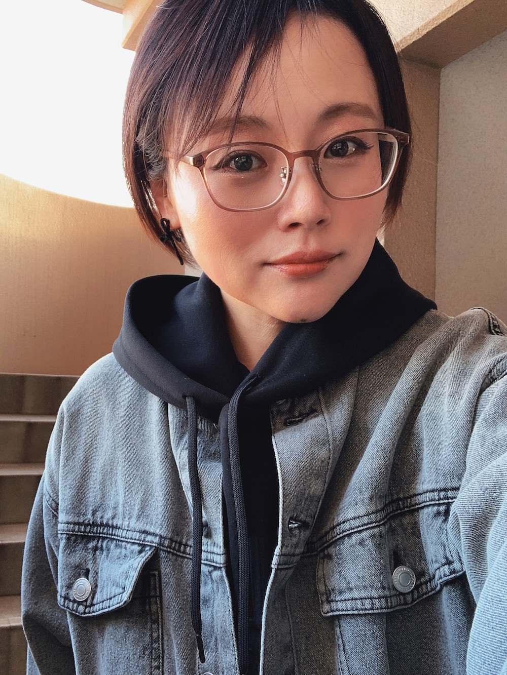 ブラック系のパーカー、ブラック系のデニムジャケット、グリーン系のパンツを着用したレディースの春コーディネートの2枚目の写真