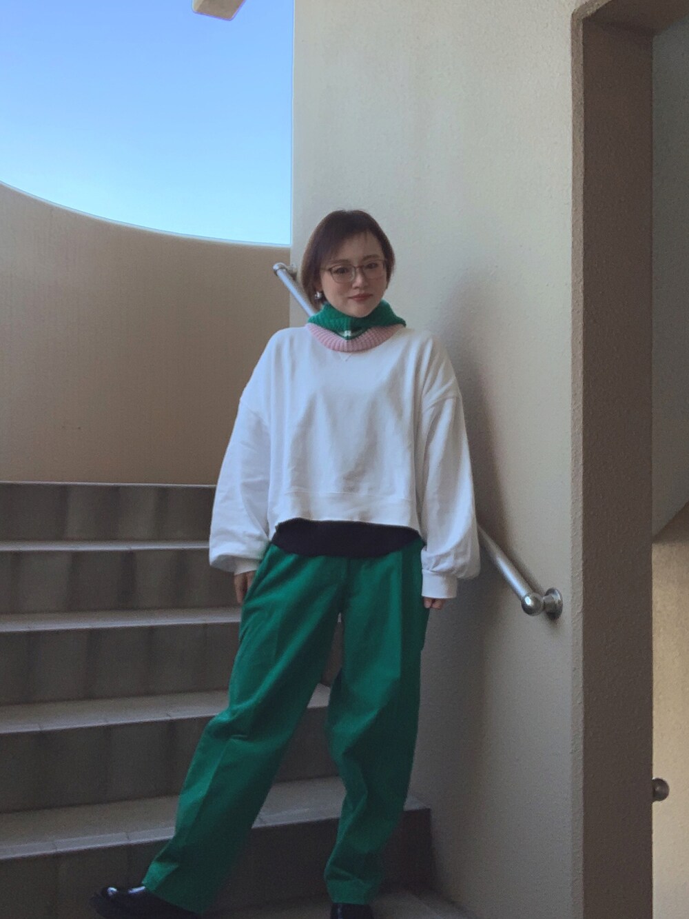 ホワイト系のスウェット、グリーン系のパンツ、ブラック系のブーツを着用したレディースの春コーディネートの2枚目の写真