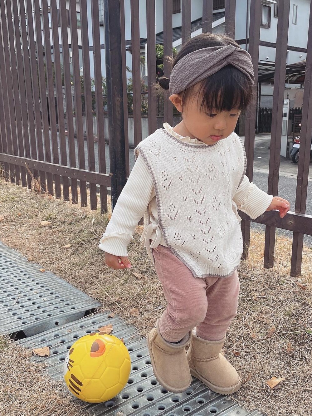 ホワイト系のベスト、ピンク系のパンツ、ベージュ系のブーツを着用したキッズの秋コーディネートの3枚目の写真