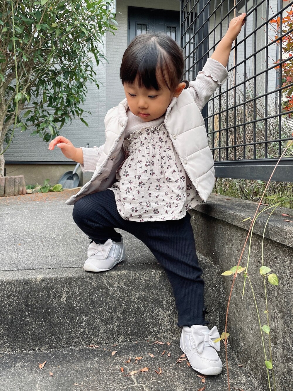 ホワイト系のダウンベスト、グレー系のTシャツ/カットソー、ブラック系のパンツを着用したキッズの秋コーディネートの4枚目の写真