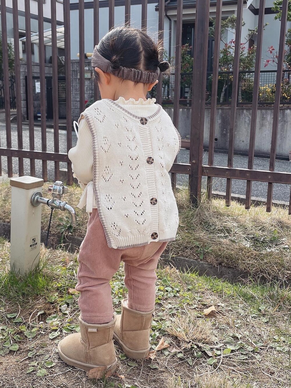 ホワイト系のベスト、ピンク系のパンツ、ベージュ系のブーツを着用したキッズの秋コーディネートの2枚目の写真