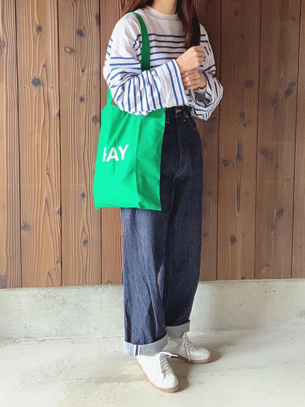 ブルー系のデニムパンツ、ブルー系のTシャツ/カットソー、グリーン系のトートバッグを着用したレディースの春コーディネートの3枚目の写真