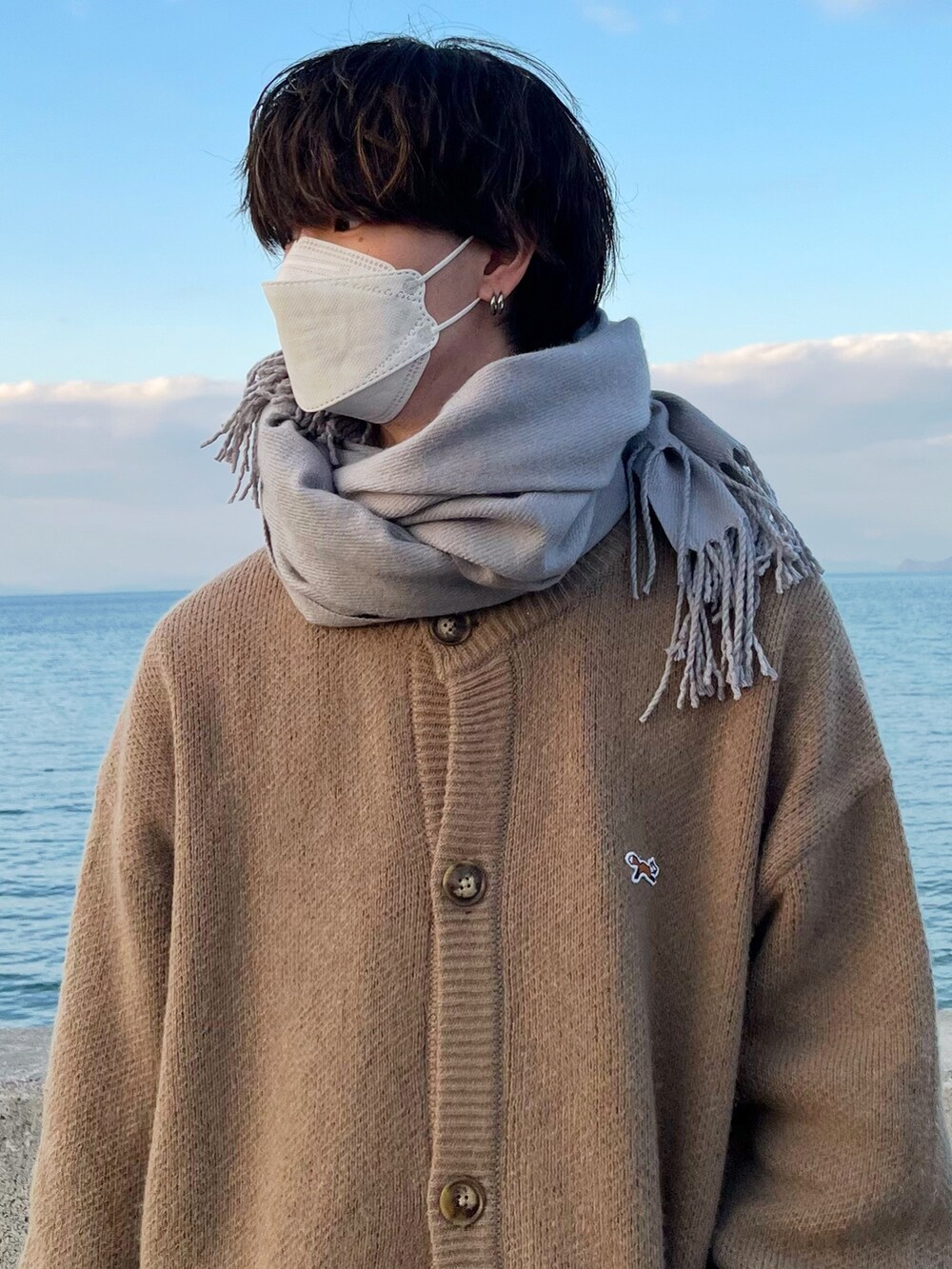 ベージュ系のカーディガン/ボレロ、ホワイト系のその他パンツ、グレー系のマフラーを着用したメンズの冬コーディネートの6枚目の写真