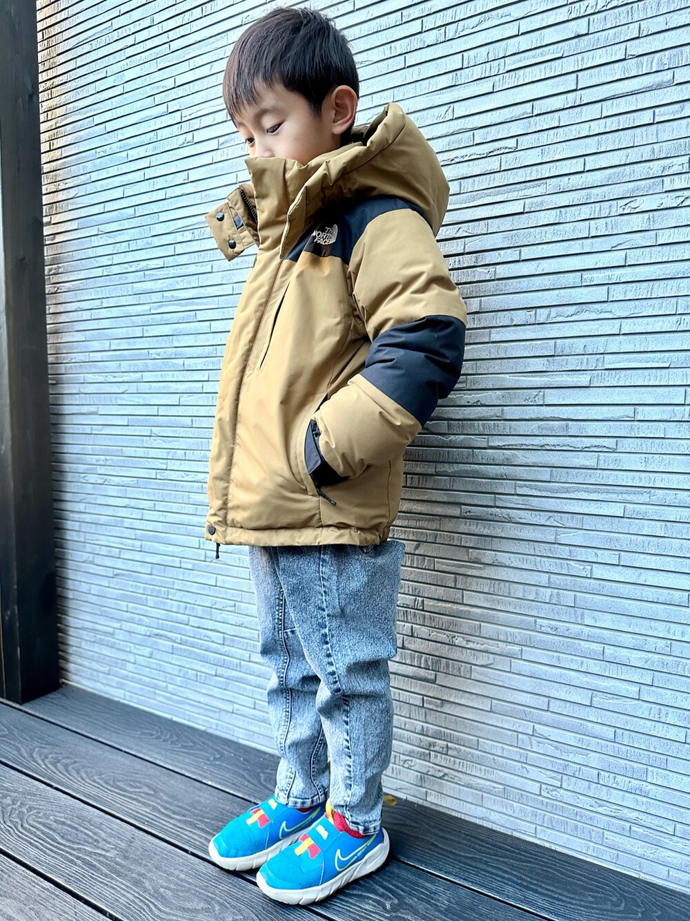 ベージュ系のダウンジャケット/コート、ブルー系のニット/セーター、その他のデニムパンツを着用したキッズの冬コーディネートの3枚目の写真