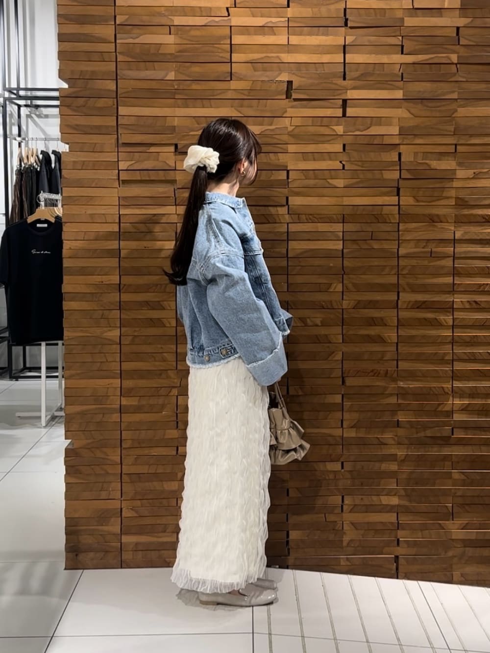 ホワイト系のスカート、ブルー系のデニムジャケット、ベージュ系のハンドバッグを着用したレディースの春コーディネートの2枚目の写真