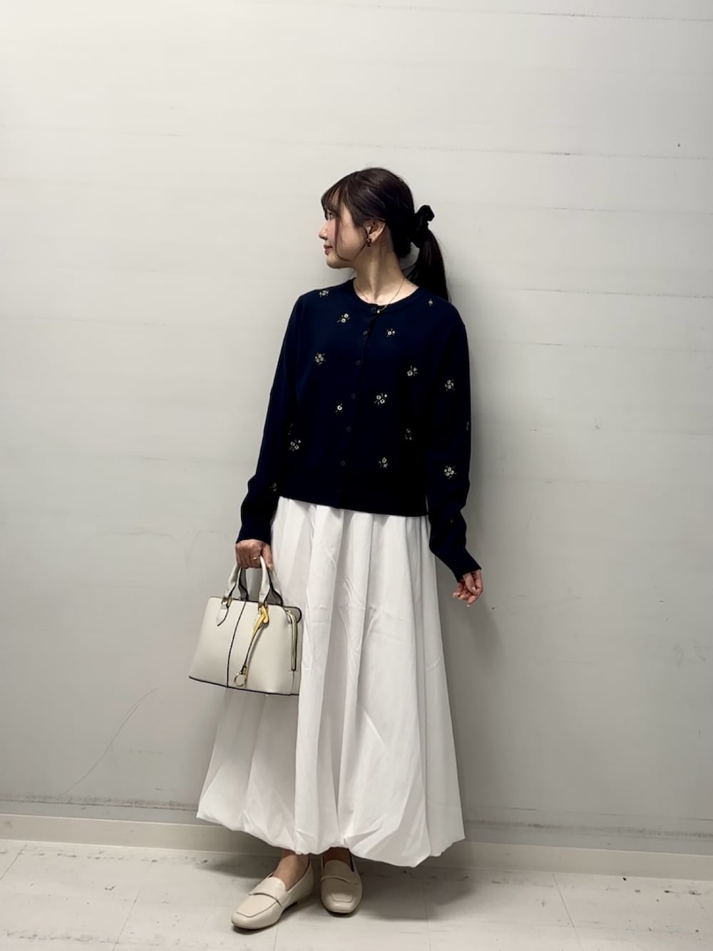 ブルー系のカーディガン/ボレロ、ホワイト系のスカート、ベージュ系のローファーを着用したレディースの冬コーディネートの2枚目の写真