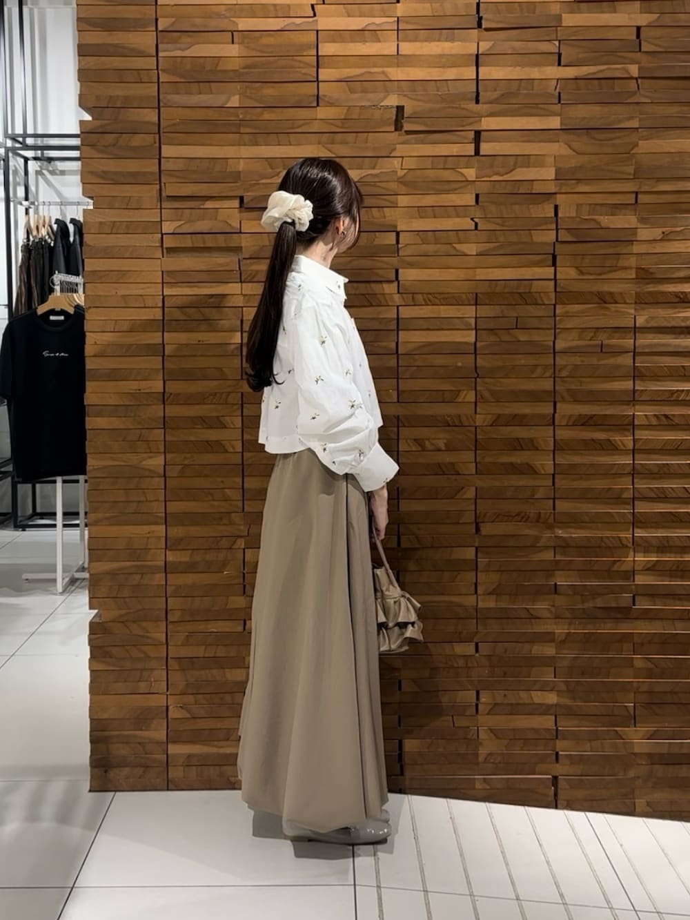 ベージュ系のスカート、ベージュ系のハンドバッグ、ホワイト系のシャツ/ブラウスを着用したレディースの春コーディネートの2枚目の写真