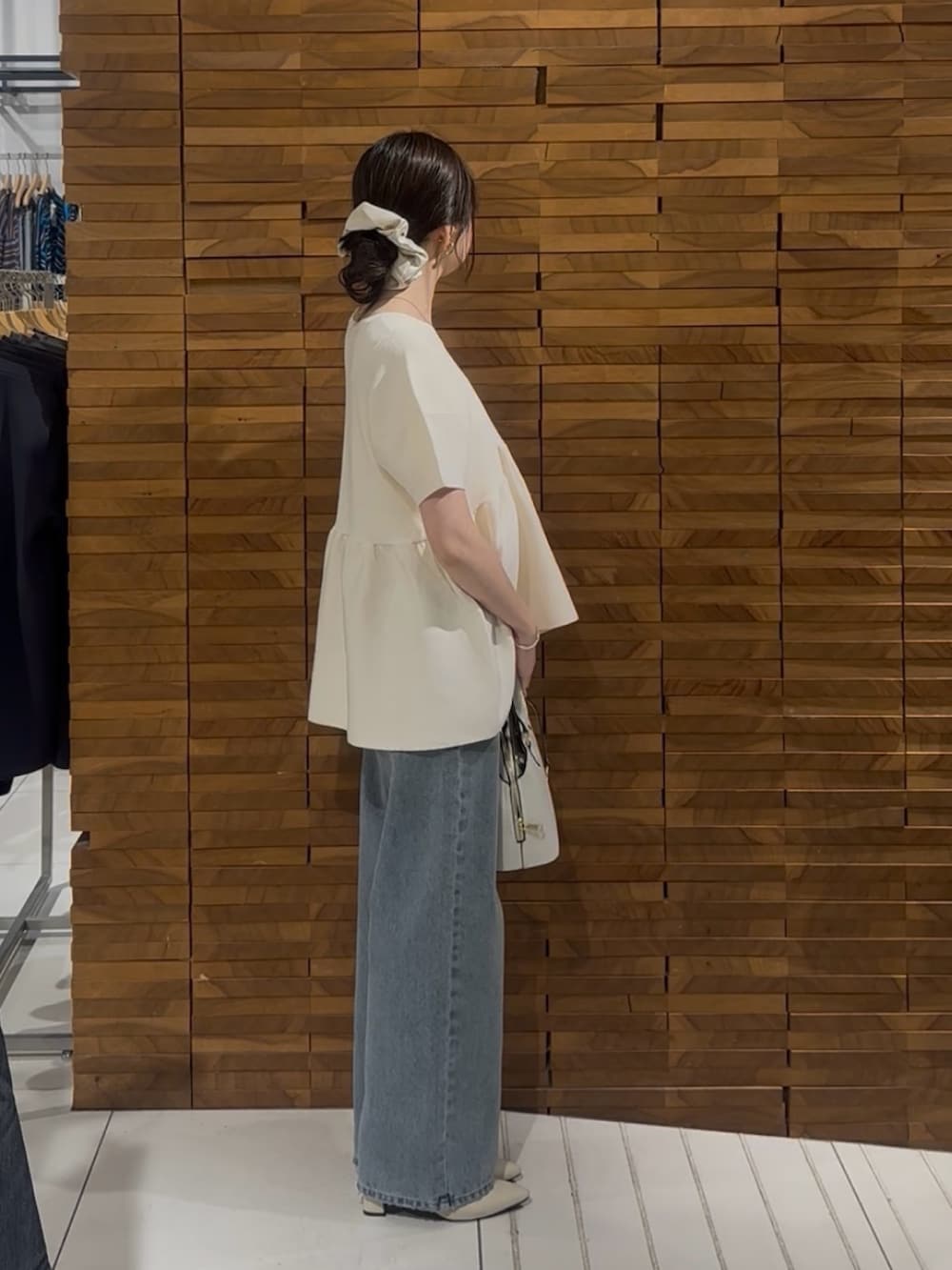ブルー系のデニムパンツ、ホワイト系のハンドバッグを着用したレディースの春コーディネートの2枚目の写真