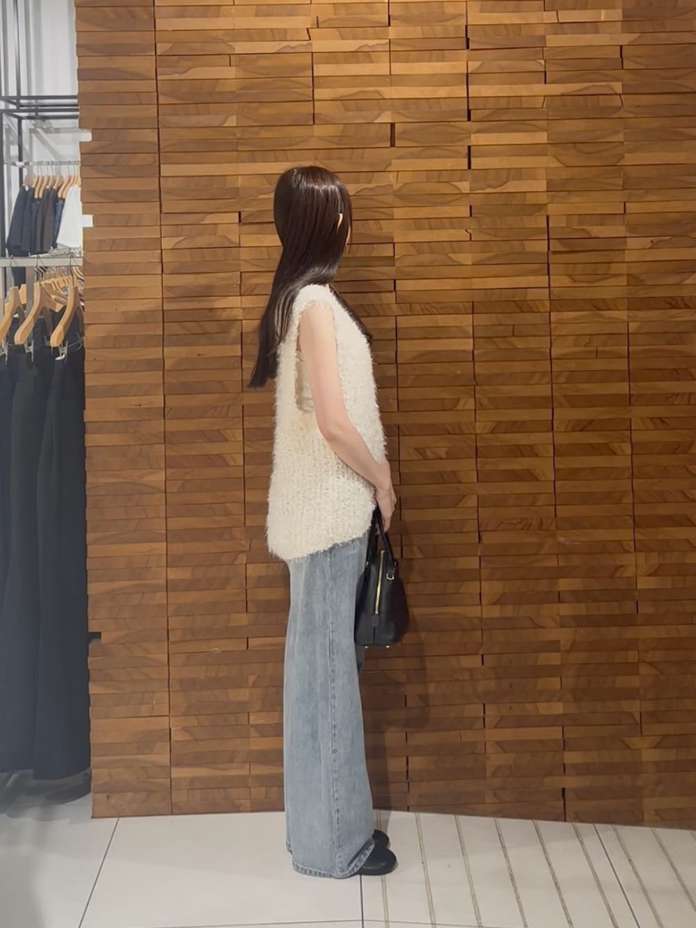 ホワイト系のベスト、ブルー系のデニムパンツを着用したレディースの夏コーディネートの2枚目の写真