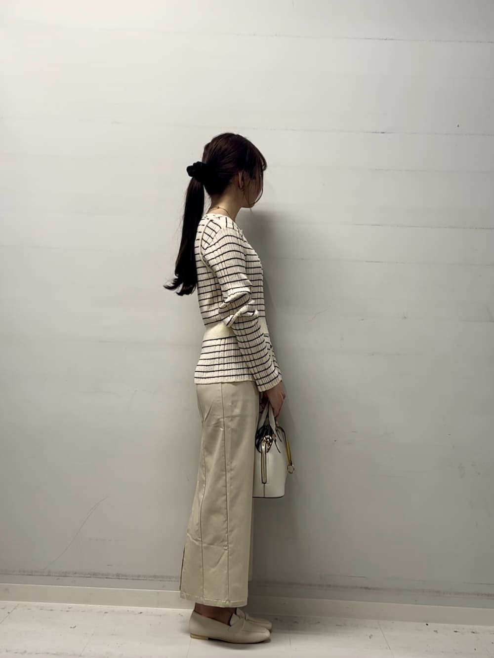 ベージュ系のスカート、ホワイト系のニット/セーター、ベージュ系のローファーを着用したレディースの冬コーディネートの2枚目の写真