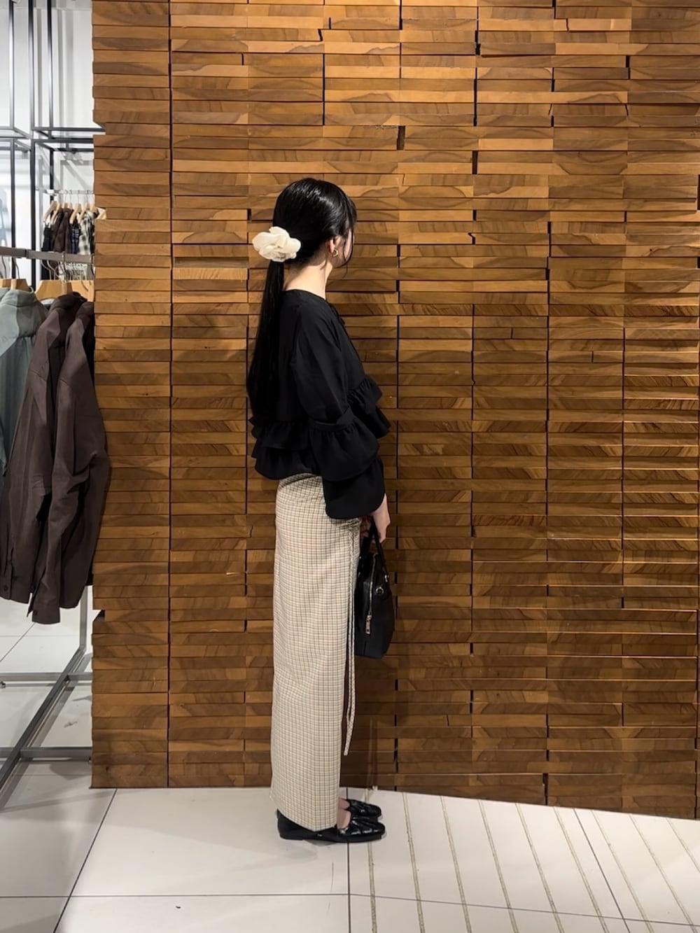 ブラック系のシャツ/ブラウス、ホワイト系のスカート、ブラック系のパンプスを着用したレディースの春コーディネートの2枚目の写真