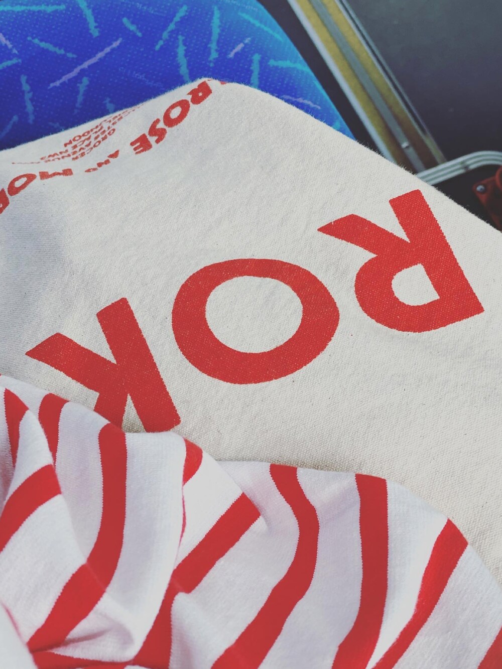 レッド系のTシャツ/カットソー、ベージュ系のチノパンツ、ベージュ系のトートバッグを着用したレディースの春コーディネートの3枚目の写真