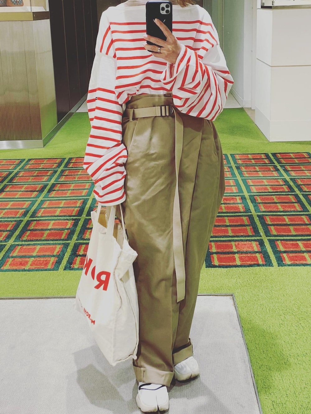 レッド系のTシャツ/カットソー、ベージュ系のチノパンツ、ベージュ系のトートバッグを着用したレディースの春コーディネートの2枚目の写真