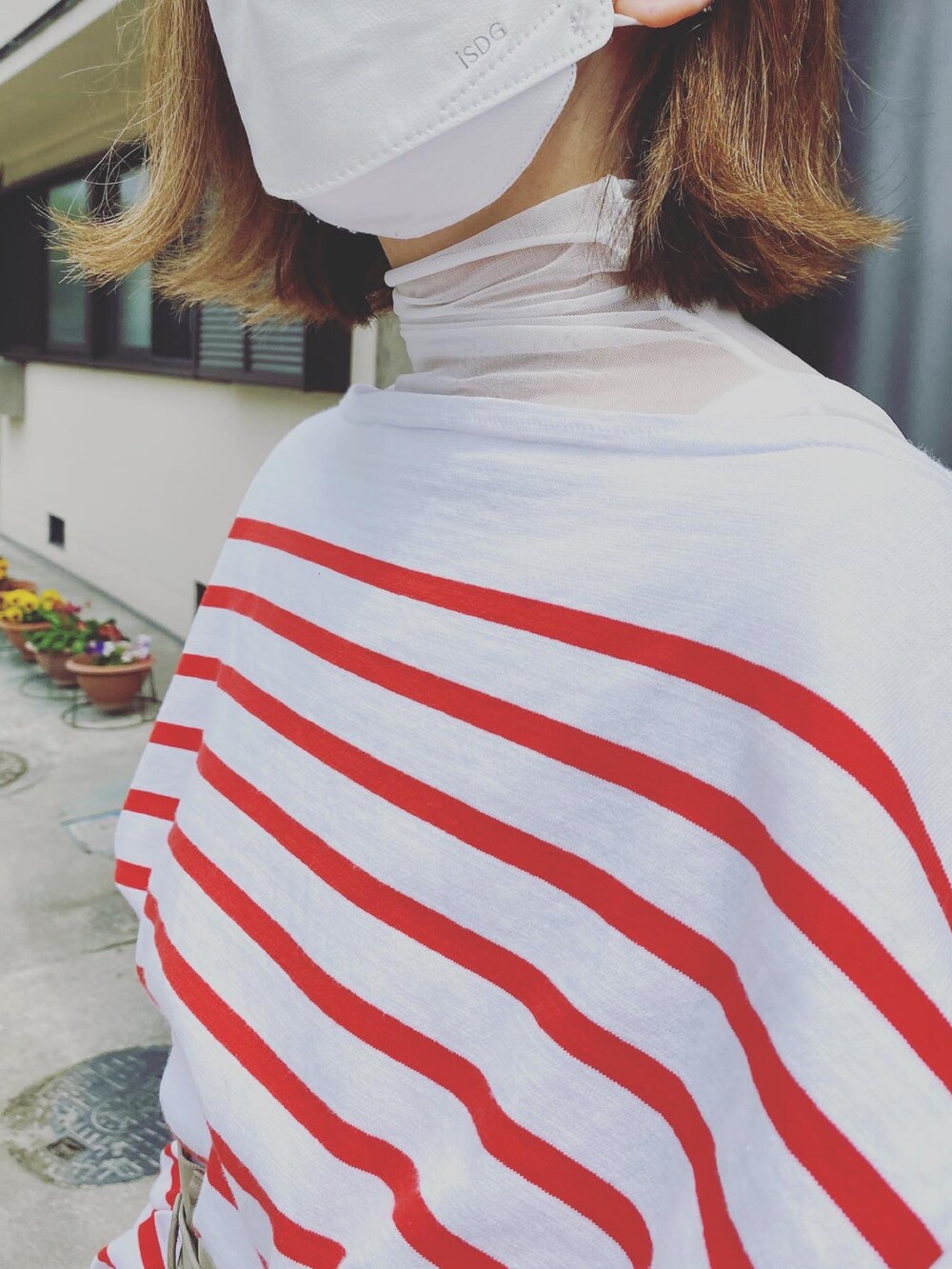 レッド系のTシャツ/カットソー、ベージュ系のチノパンツ、ベージュ系のトートバッグを着用したレディースの春コーディネートの2枚目の写真