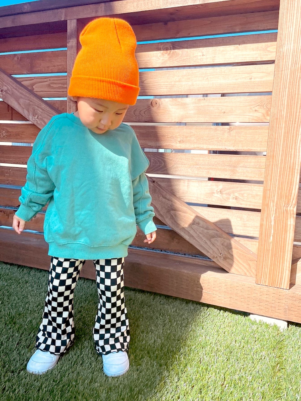 グリーン系のスウェット、ブラック系のその他パンツ、オレンジ系のニットキャップ/ビーニーを着用したキッズの春コーディネートの2枚目の写真