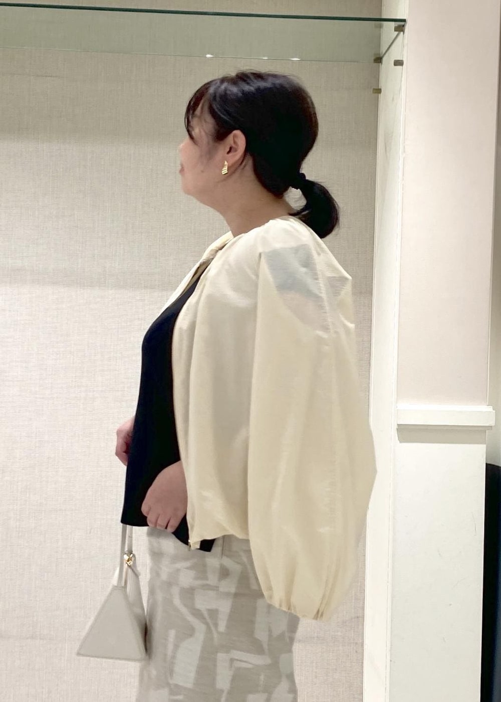 ホワイト系のハンドバッグ、シルバー系のパンプス、ブラック系のニット/セーターを着用したレディースの春コーディネートの3枚目の写真
