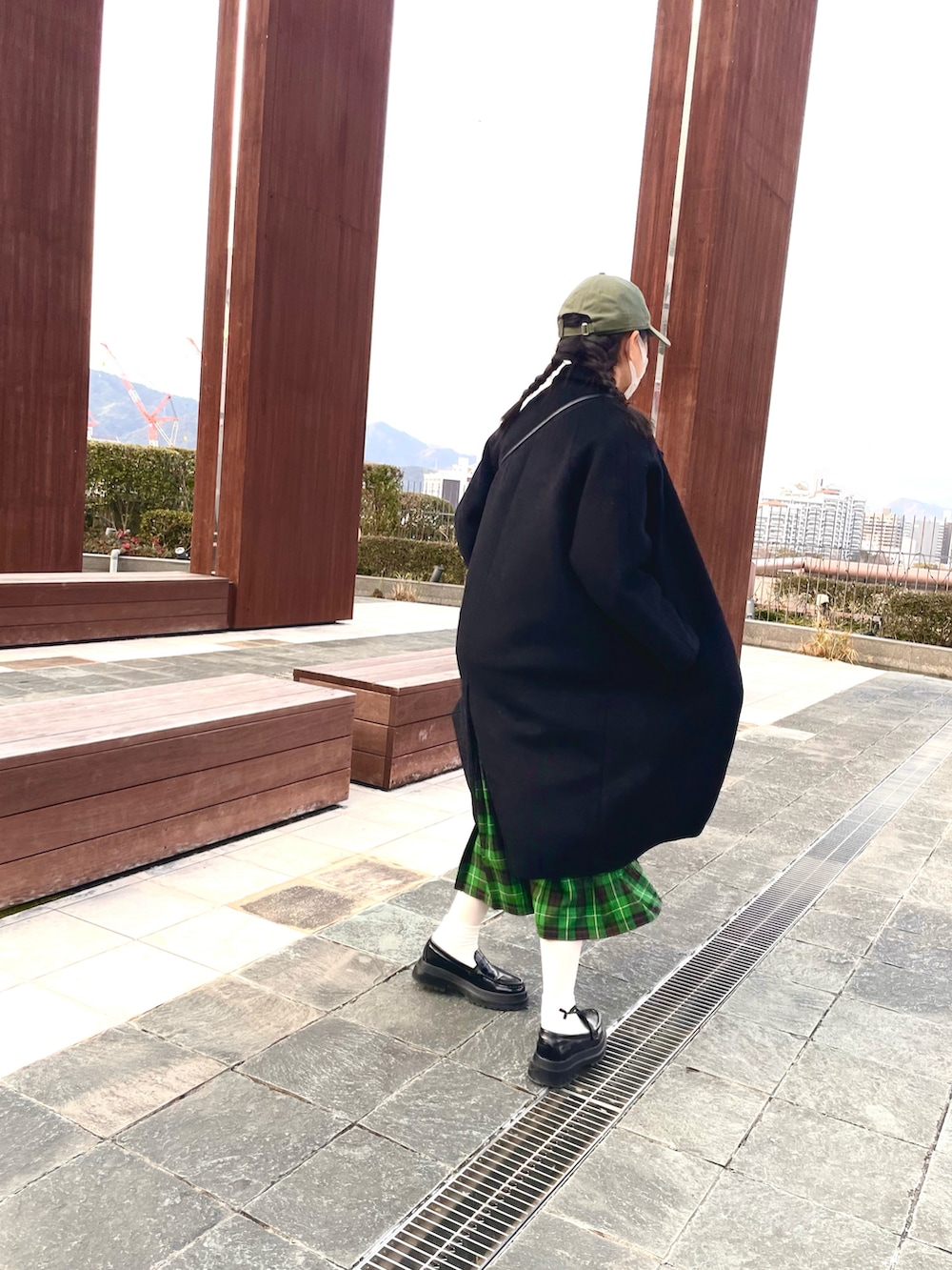 ブラック系のステンカラーコート、グリーン系のキャップを着用したキッズの冬コーディネートの2枚目の写真