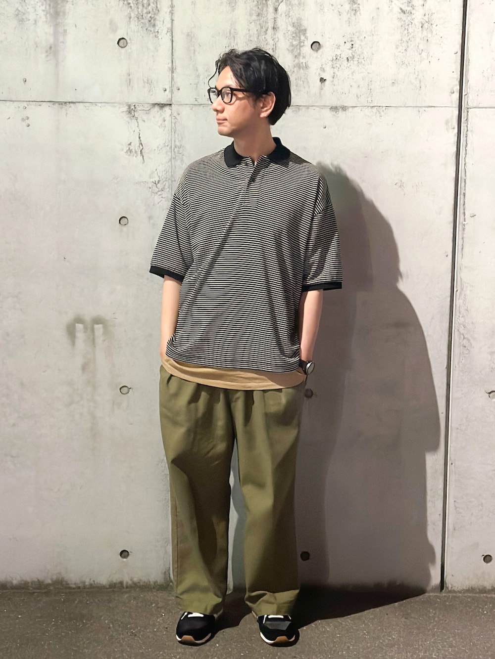 ブルー系のポロシャツ、グリーン系のスラックス、ブラック系のスニーカーを着用したメンズの春コーディネートの2枚目の写真