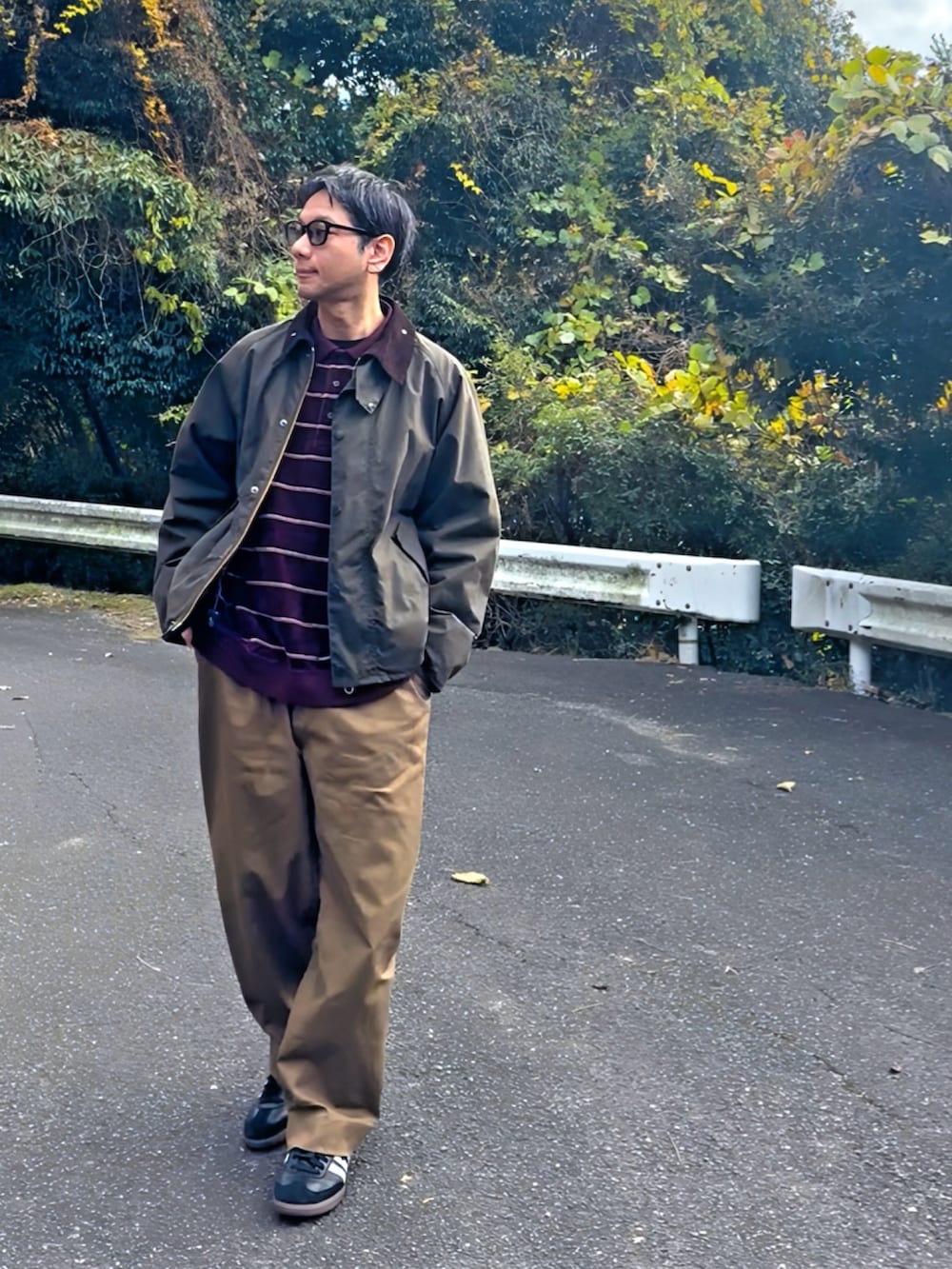 グリーン系のブルゾン、ブラウン系のスラックス、ブラック系のスニーカーを着用したメンズの冬コーディネートの2枚目の写真